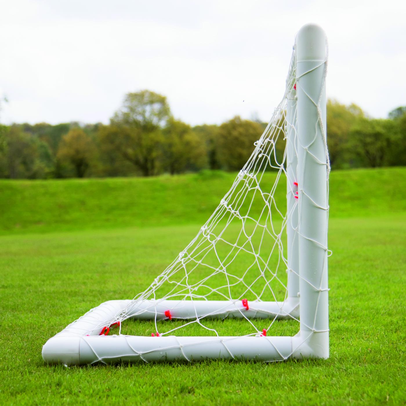 Mini-but de football Q-FOLD 90 x 75 cm vu de côté sur l'herbe, montrant la profondeur du filet.