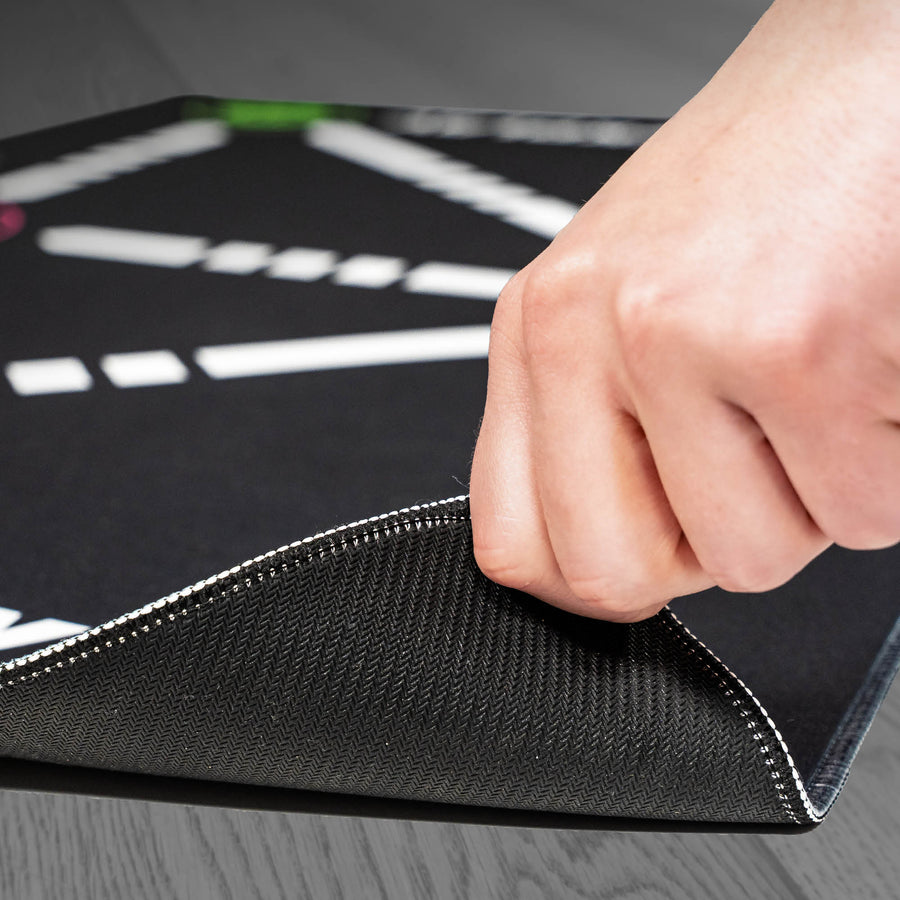 Coin du tapis d'entraînement de football pour la maîtrise du ballon soulevé à la main, montrant le dessous noir texturé et la bordure cousue.