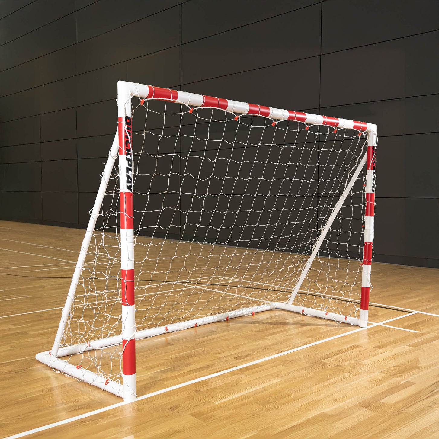 But de minihand pliable Q-FOLD 240 x 170 cm avec un cadre rouge et blanc et un filet blanc, posé sur le parquet d'une salle de sport.
