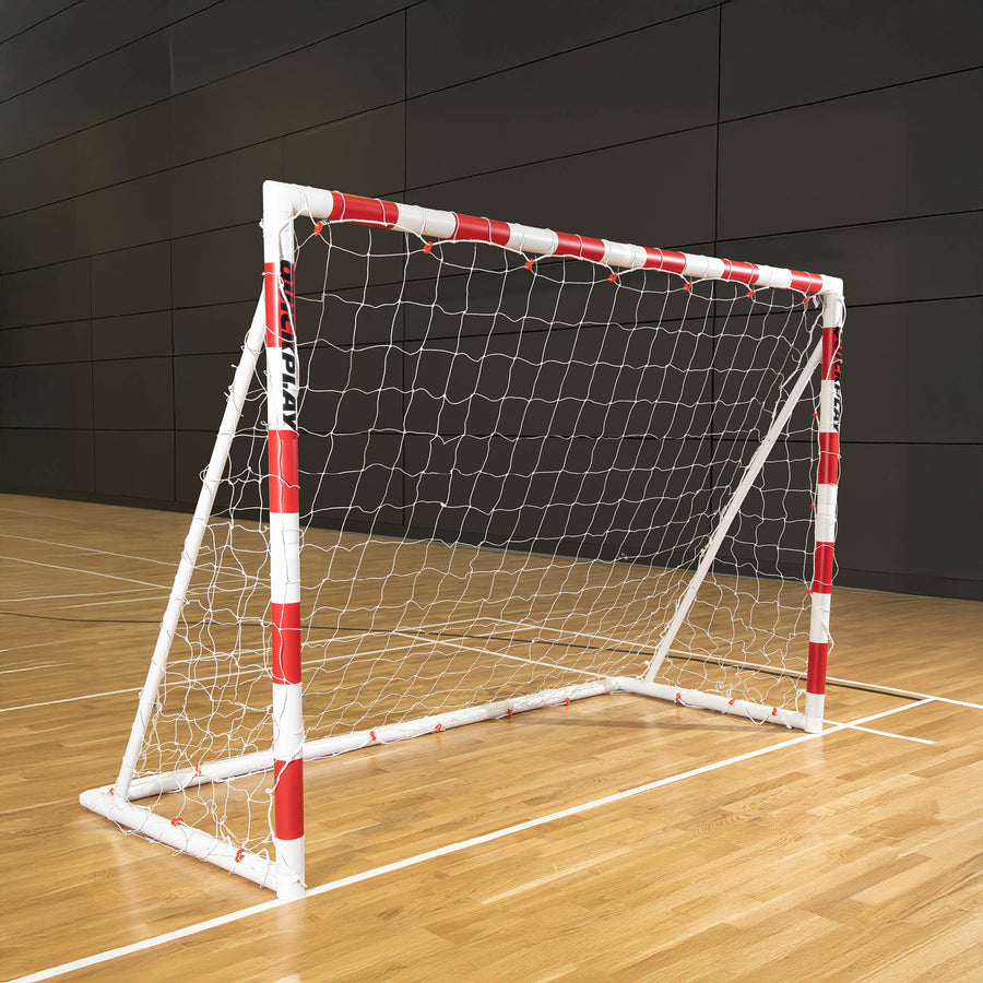 But de minihand pliable Q-FOLD 240 x 170 cm avec un cadre rouge et blanc et un filet blanc, posé sur le parquet d'une salle de sport.