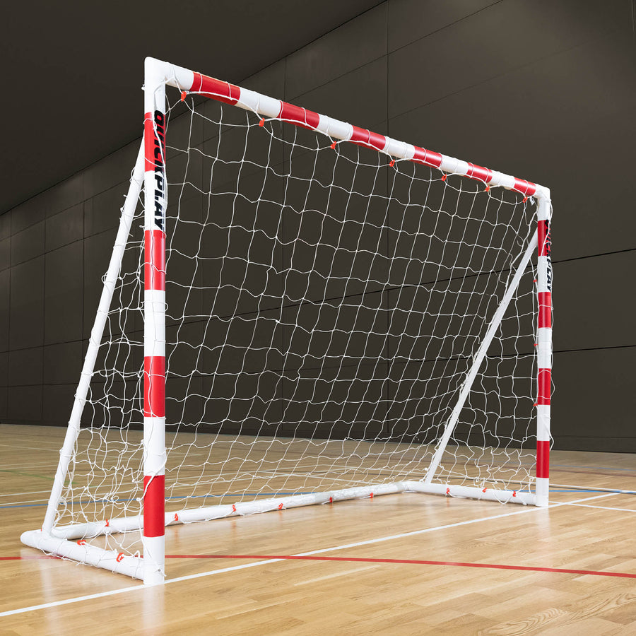 But de handball pliable Q-FOLD 300 x 200 cm avec des poteaux rayés rouge et blanc et un filet blanc, sur le parquet d'une salle de sport.