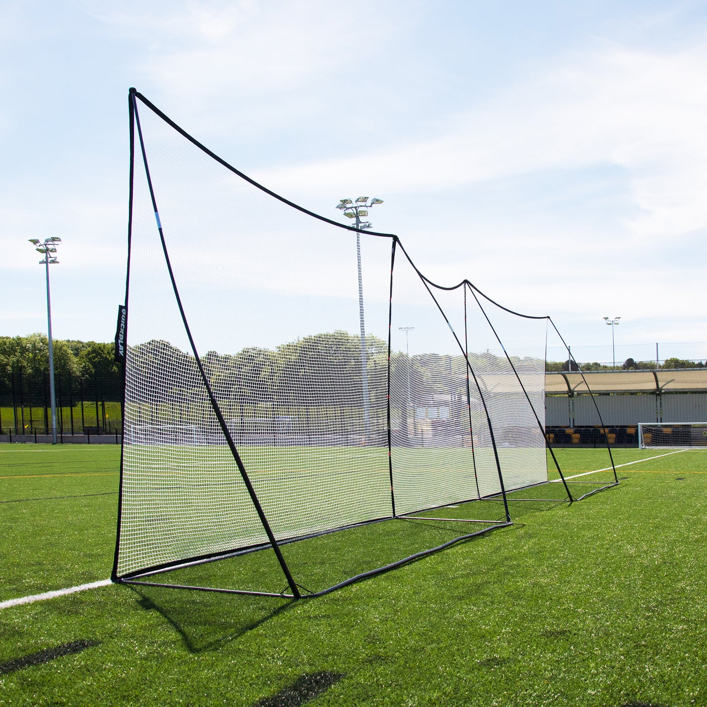 Filet d'extension 240 x 270 cm vu depuis l'extrémité d'une longue rangée, reliant deux MEGA NET avec des mâts noirs et des cadres de base.