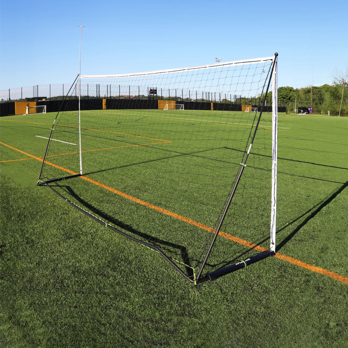 But KICKSTER Elite 500 x 200 cm vu de derrière sur un terrain synthétique, montrant le cadre arrière noir et le filet.