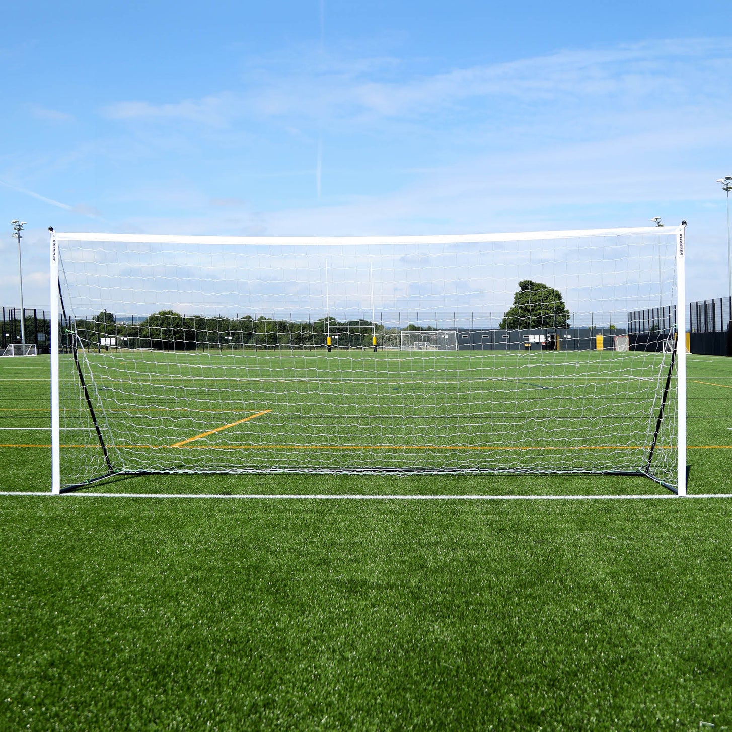 But KICKSTER Elite 500 x 200 cm vu de face sur un terrain synthétique, cadre blanc et filet blanc.