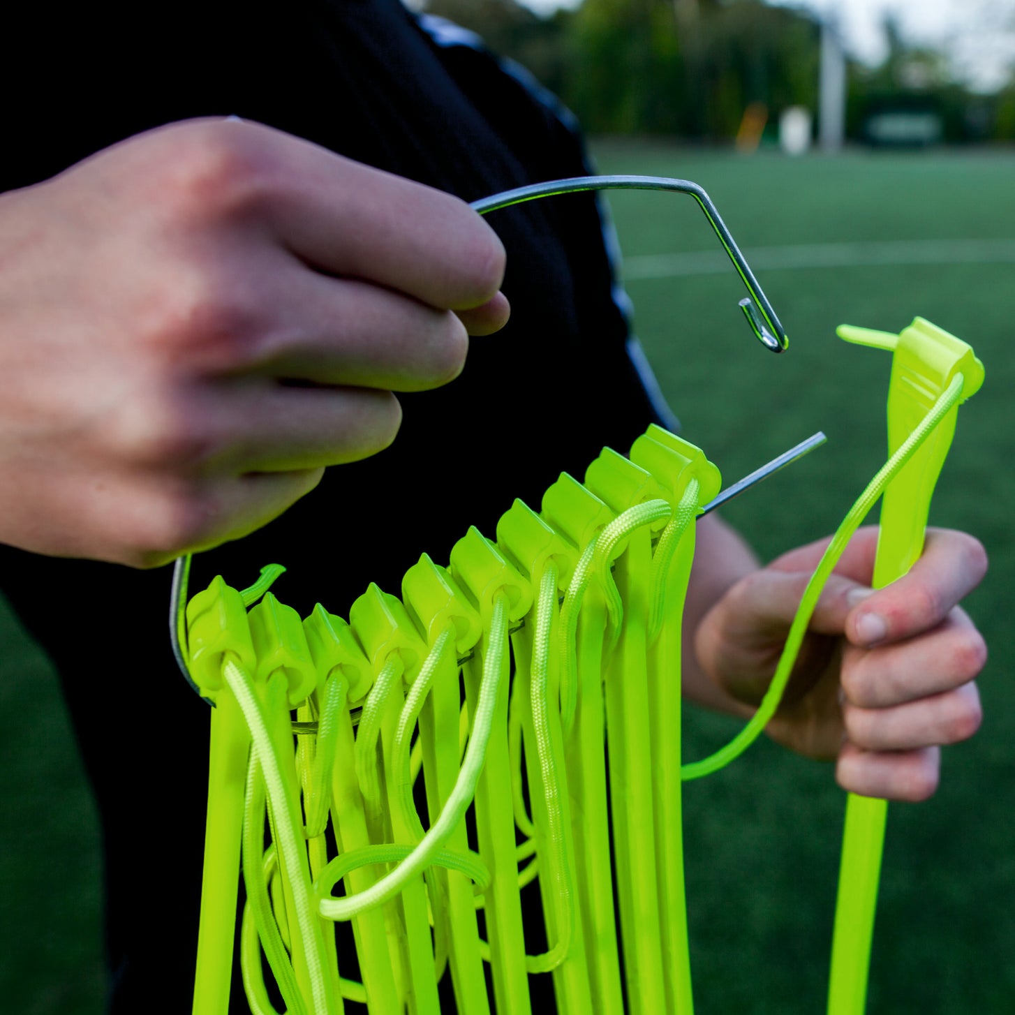 Gros plan de mains glissant les barreaux jaunes de l'échelle de rythme sur un crochet métallique pour le rangement.