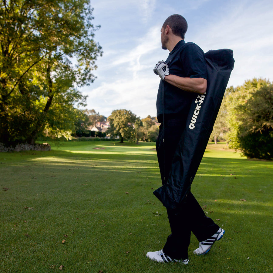 Golfeur portant sur l'épaule le filet de golf QUICK-HIT rangé dans son sac noir QUICK-HIT, sur un parcours de golf.