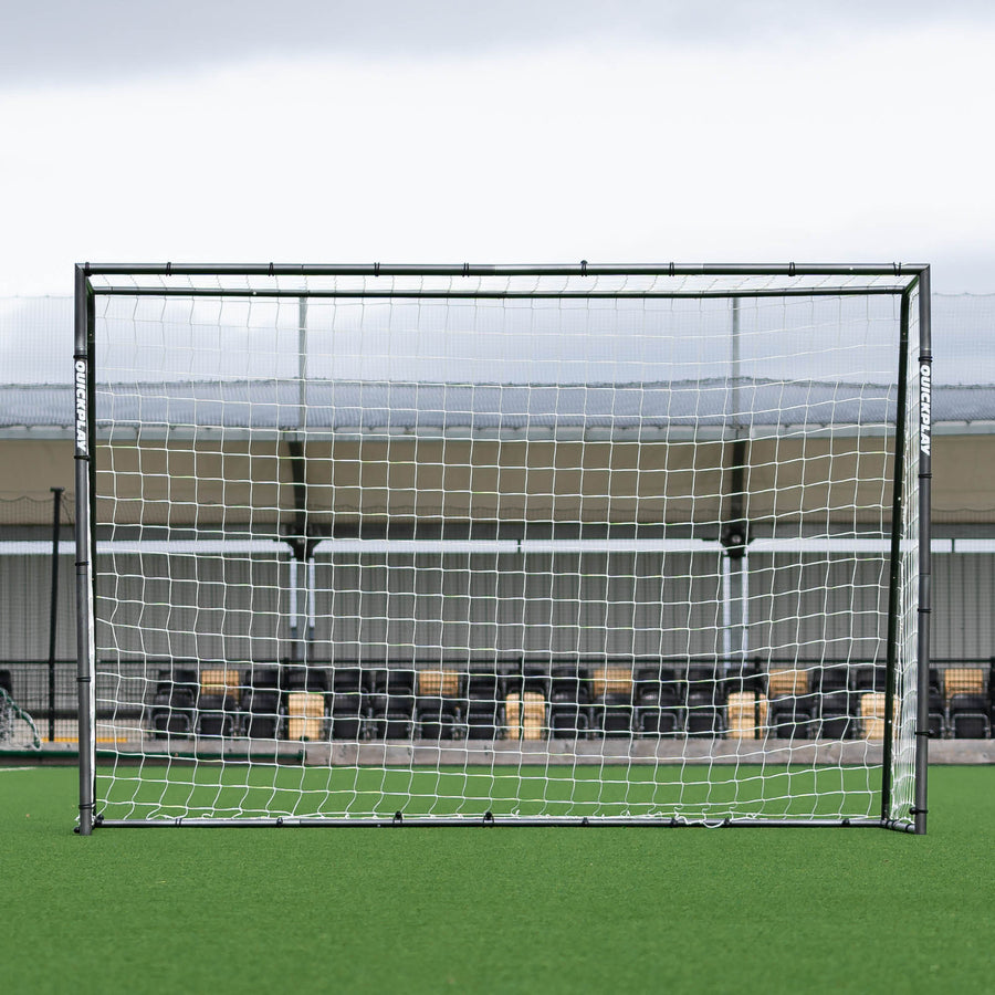 But de futsal GS Series 300 x 200 cm vu de face, devant une tribune au bord d'un terrain synthétique.