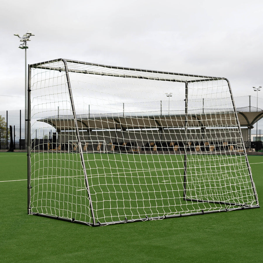 But de futsal GS Series 300 x 200 cm en contre-plongée sur un terrain synthétique, sous un ciel nuageux avec des projecteurs derrière.