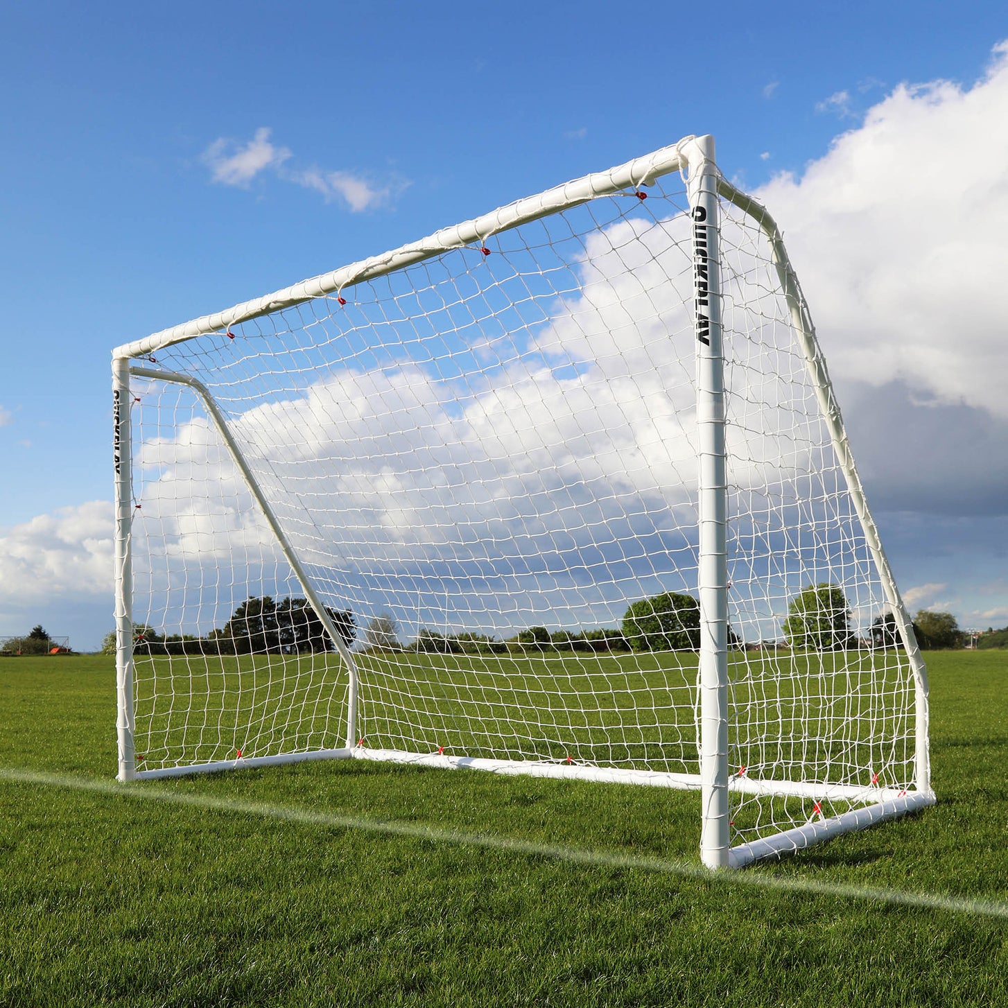 But de futsal pliable Q-FOLD Match 300 x 200 cm avec cadre et filet blancs, posé sur l'herbe sous un ciel bleu.