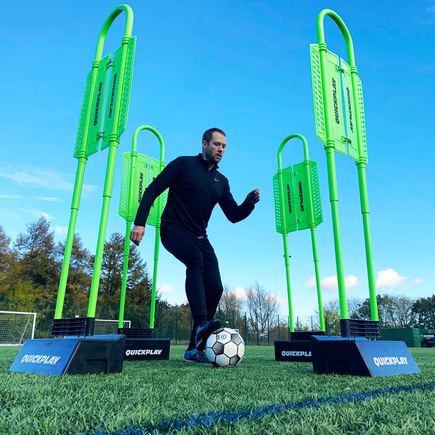 Mannequin défenseur REPLAY avec base Block en contre-plongée : joueur dribblant entre quatre mannequins verts dans des bases noires.