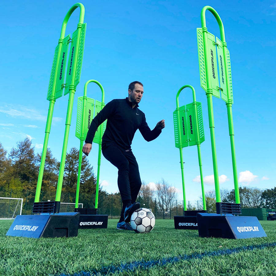 Mannequin défenseur REPLAY avec base Block en contre-plongée : joueur dribblant entre quatre mannequins verts dans des bases noires.