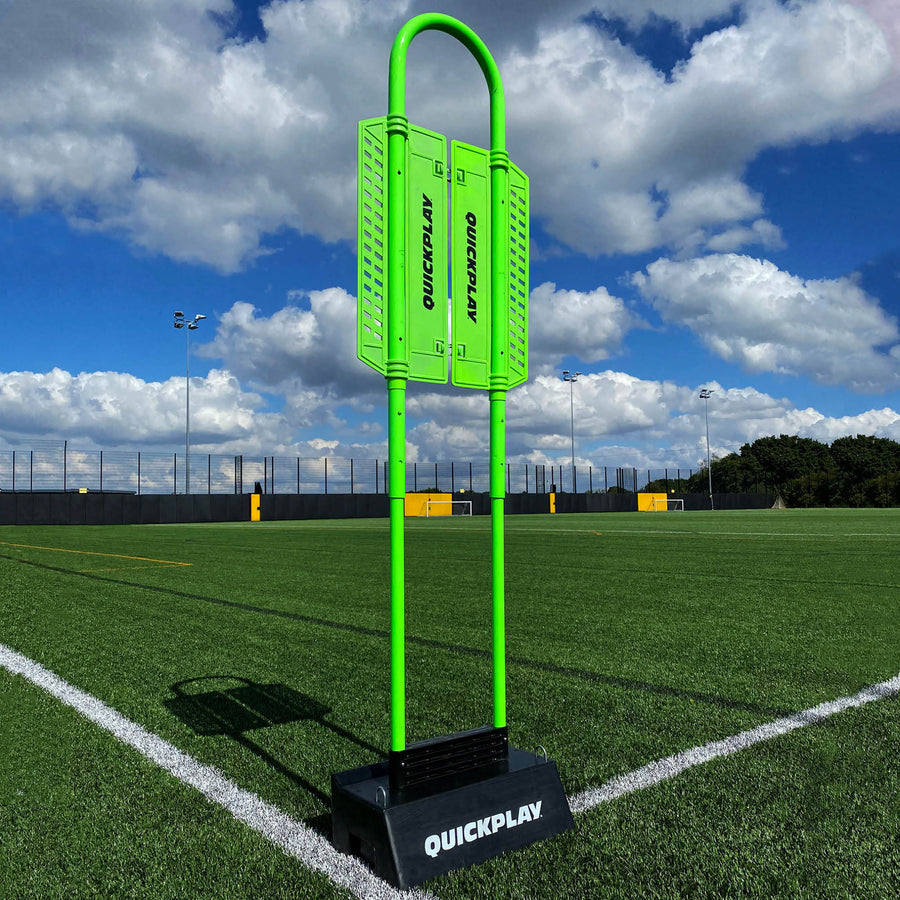Mannequin défenseur REPLAY avec base de rebond Block : mannequin vert avec panneaux QUICKPLAY, dressé dans une base noire QUICKPLAY sur un terrain synthétique.