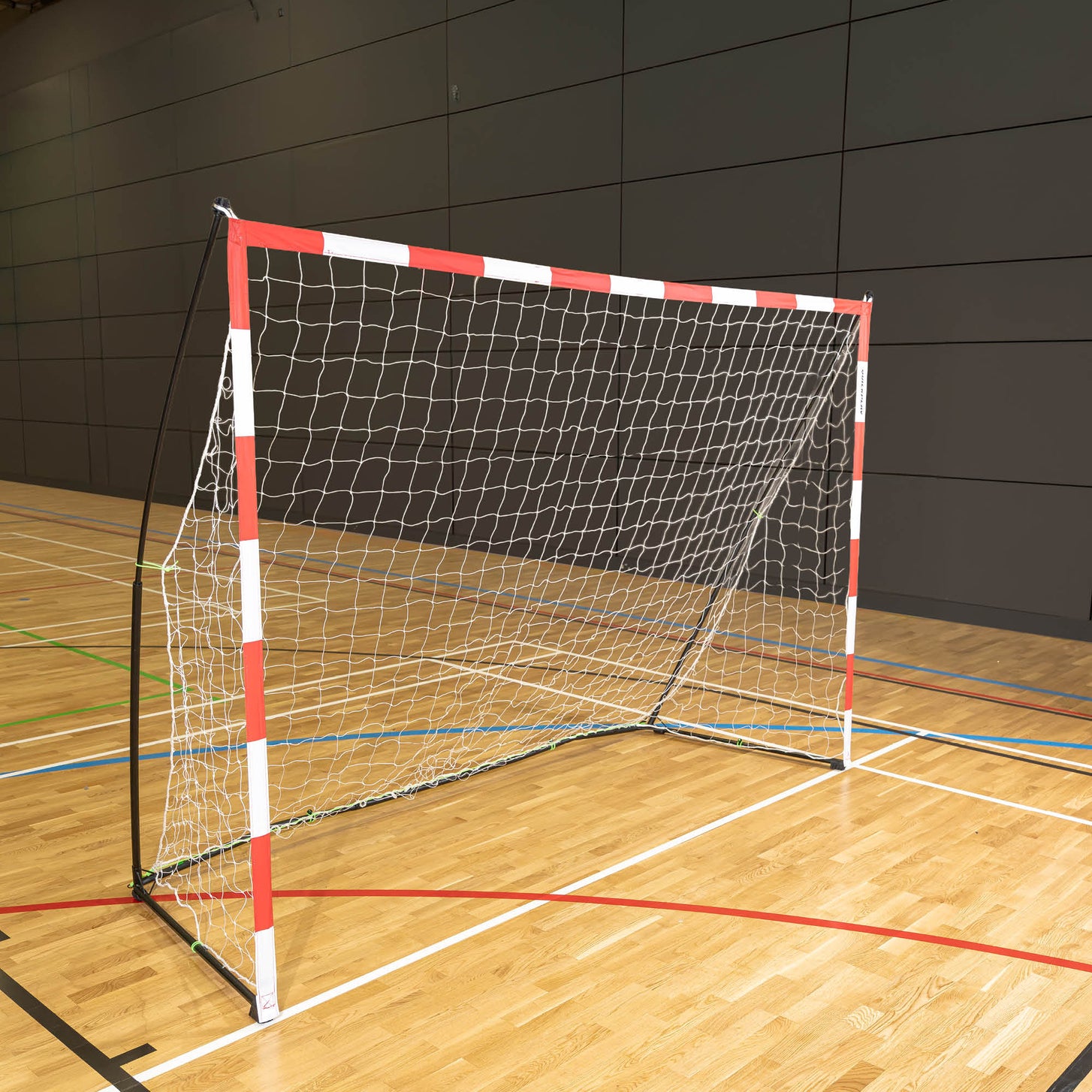 But de handball transportable 300 x 200 cm avec cadre rouge et blanc et filet blanc, posé sur le parquet d'une salle de sport.