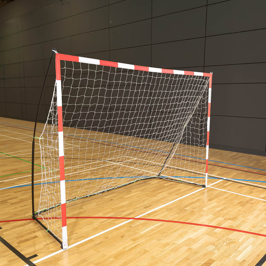 But de handball transportable 300 x 200 cm avec cadre rouge et blanc et filet blanc, posé sur le parquet d'une salle de sport.