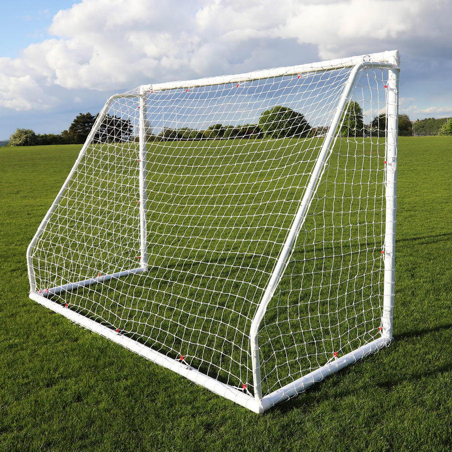 But Q-FOLD Match 300 x 200 cm vu de l'arrière en biais sur l'herbe, montrant la profondeur du cadre et du filet.