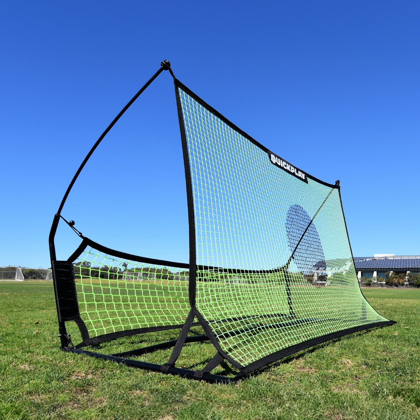 Rebondisseur de football à double filet TEKKERS Trainer sur l'herbe, montrant son grand filet vert avec un cercle cible foncé et le filet inférieur.