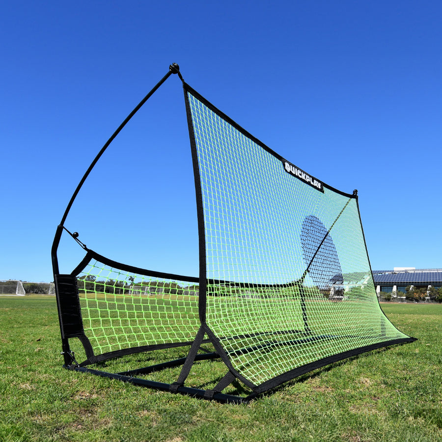 Rebondisseur de football à double filet TEKKERS Trainer sur l'herbe, montrant son grand filet vert avec un cercle cible foncé et le filet inférieur.