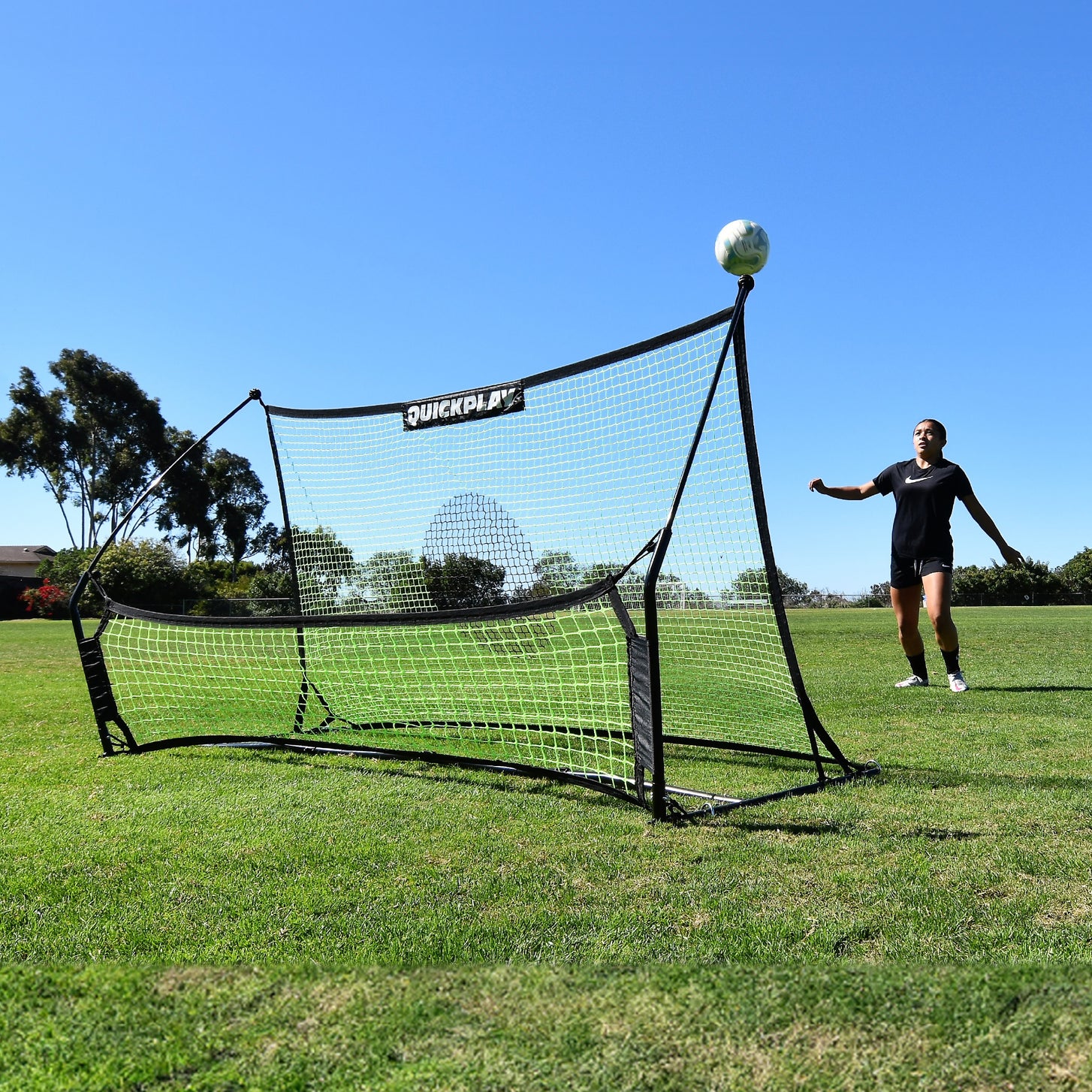 Joueur attendant un ballon qui rebondit vers le haut sur le rebondisseur de football à double filet TEKKERS Trainer, sur un terrain en herbe.
