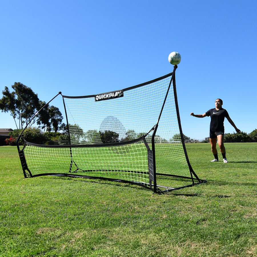 Joueur attendant un ballon qui rebondit vers le haut sur le rebondisseur de football à double filet TEKKERS Trainer, sur un terrain en herbe.